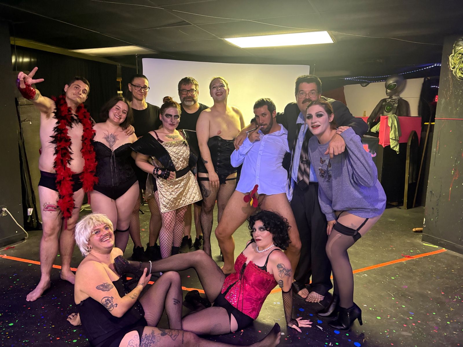 The cast posing together backstage in full costume after a show