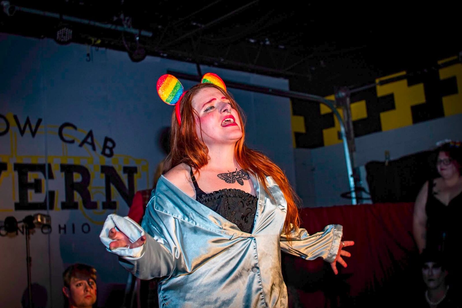 Columbia performing on stage in silver pajamas and rainbow mouse ears